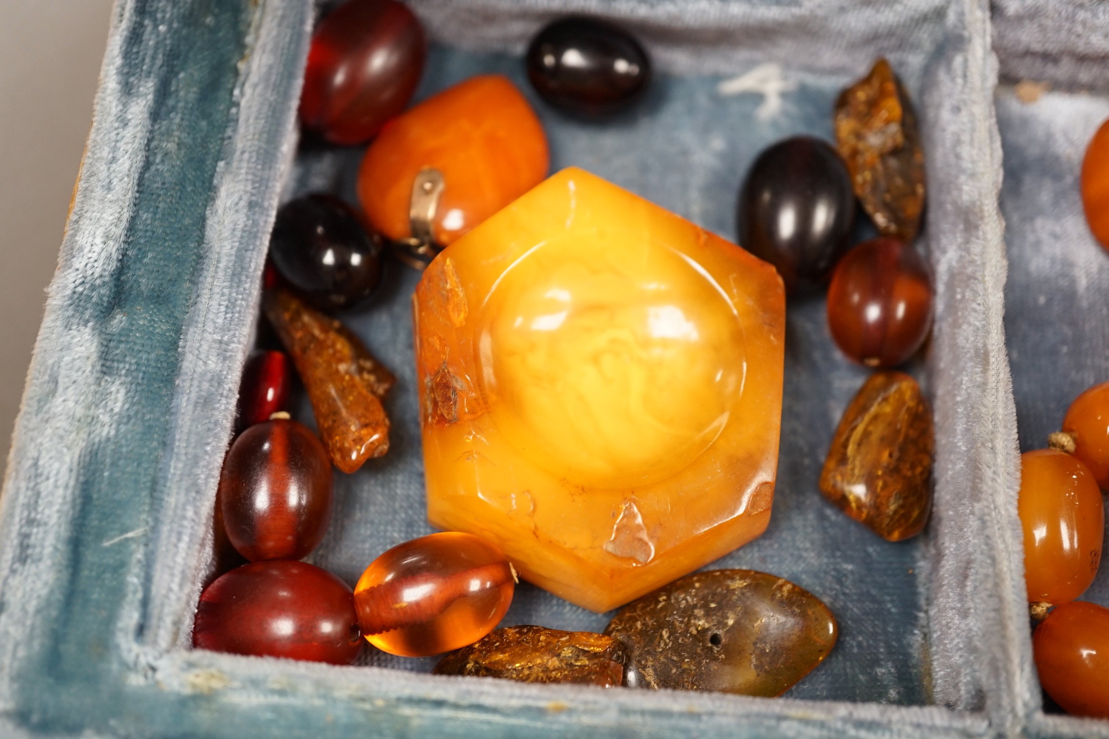 A single strand amber bead necklace, 48cm, gross 52 grams, together with other loose amber and amberoid beads and an amber pendant in a simulated book box.